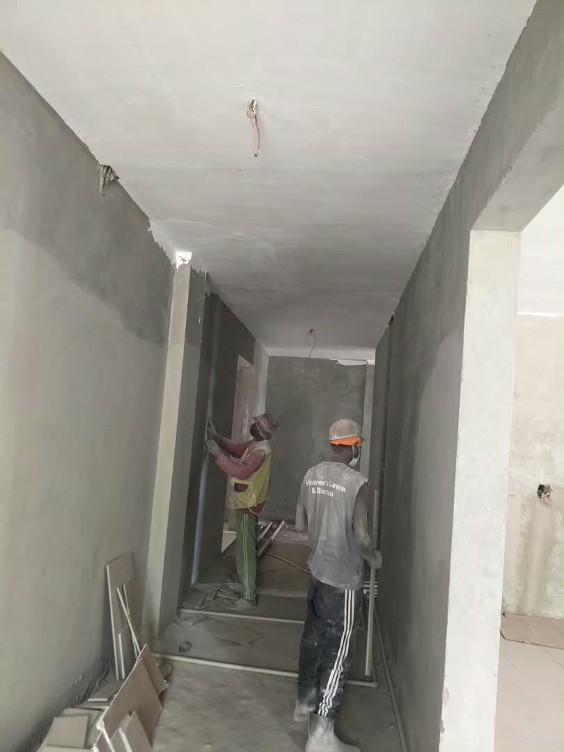 Workers plastering an internal corridor at the Dhahabu Apartments site, September 2026