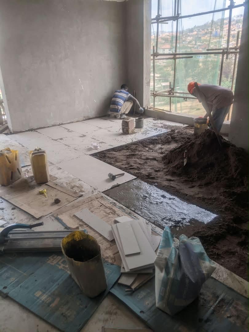 Tilers laying floor tiles in a Dhahabu residence, September 2026